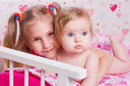 Two happy sisters hug in light roomの写真素材