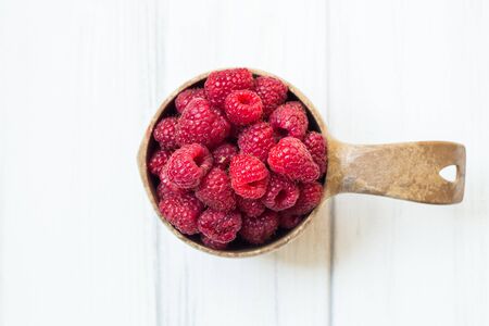 Bowl with summer raspberries on white wooden table