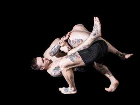Young mma fighters in sparing on black backgroundの写真素材