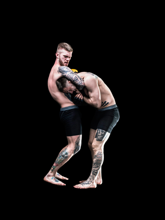 Strong and young MMA fighter holding his rival on black backgroundの写真素材