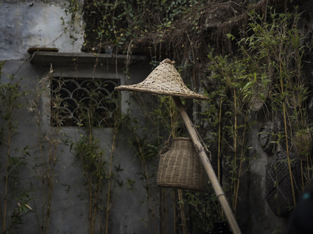 Straw hat and basket on a bamboo poleの写真素材