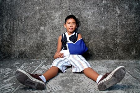 a young boy with blue sling on broken armの写真素材