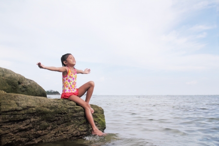 Young girl enjoying a peaceful day by the sea.の写真素材