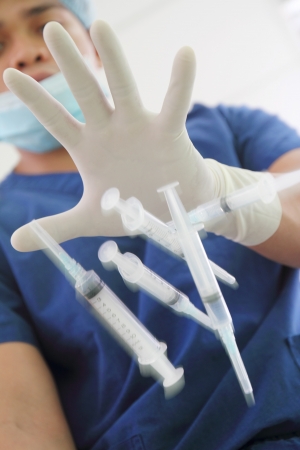 Health worker throwing a bunch of used syringes.の写真素材
