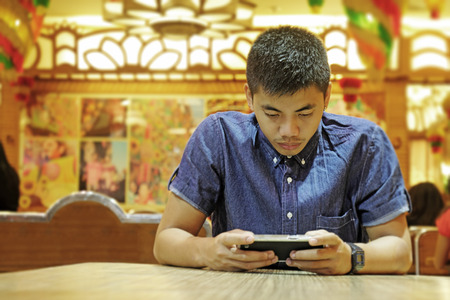 Young asian man busy with tablet computer in a restaurant.
