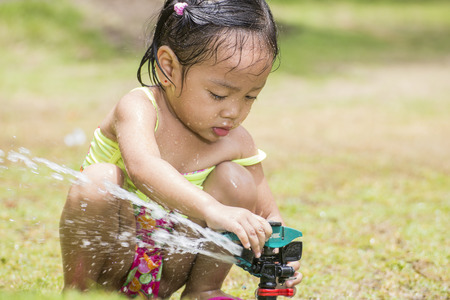 Little asian girl playing with a garden sprinkler.の写真素材