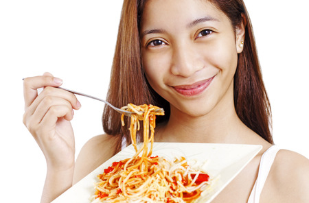 Smiling young lady holding a plate of spaghetti. Isolated in white background.の写真素材