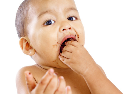 Close up portrait of a little boy eating a cake with his hand. Isolated in white background.の写真素材