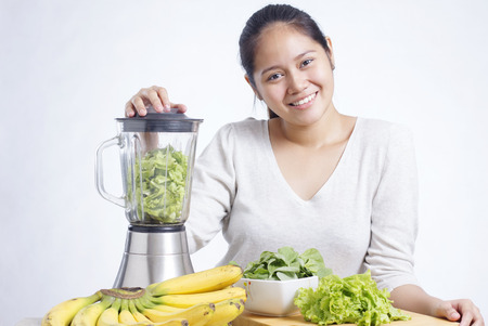 Asian lady preparing fruits and vegetables for making green smoothie.の写真素材