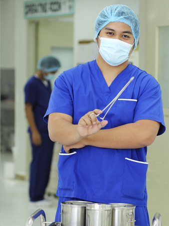 Male operating room nurse holding a medical forcep.の写真素材