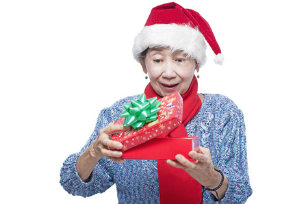 Senior lady receiving a surprise christmas gift. Isolated in white background.の写真素材