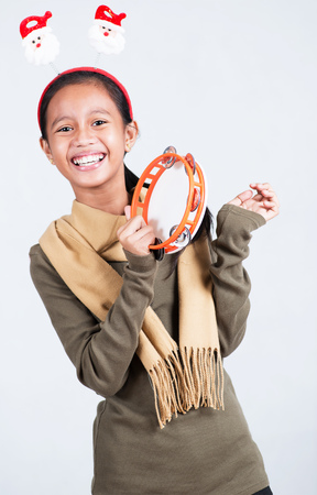 Happy and cheerful young lady with a tambourine singing christmas carol.の写真素材