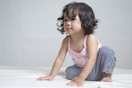 Cute little asian girl crawling in bed.