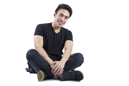 Happy handsome male model in sitting position over a white background.の写真素材