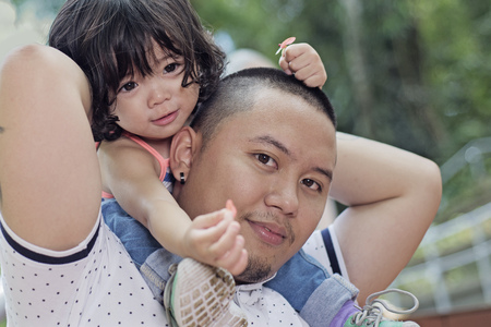 Close up portrait of a father carrying his daughter in his shoulder.の写真素材