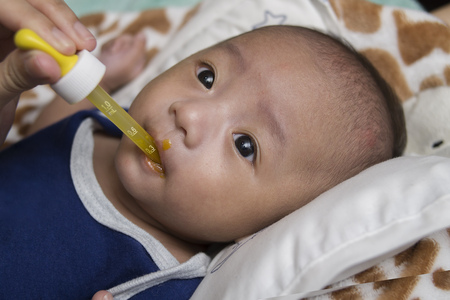 Cute little asian baby boy taking multi vitamins. Close up.の写真素材
