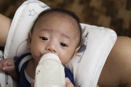 Bottle feeding of a cute little asian baby boy. Close up.の写真素材