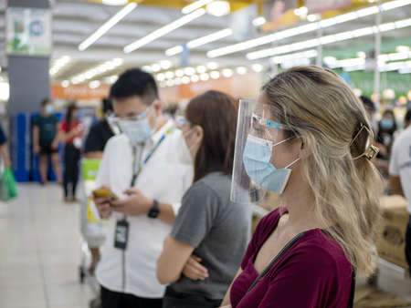 Group of people with facemask and face shield inside a building.の写真素材