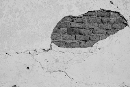 Rustic facade with peeled plaster exposing ancient clay bricks in black and whiteの写真素材
