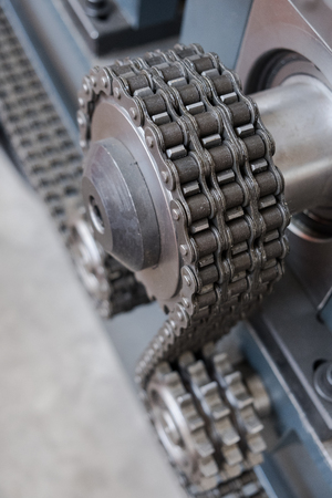 Triple strand roller chain going around three sprockets on industrial machineの写真素材