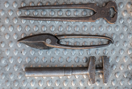 Vintage hand tools on aluminum plate close up, end cutting nippers, adjustable wrench and tin scissorsの写真素材