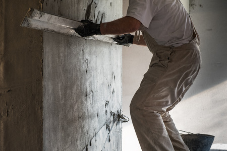 Construction worker leveling the wall surface of cement plasterの写真素材