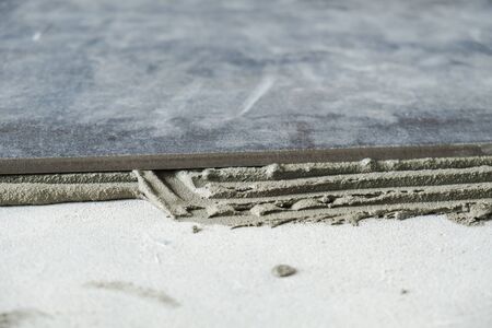 Dark grey ceramic floor tiles laid on applied adhesiveの写真素材