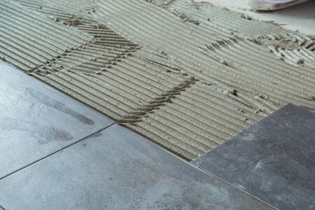 Dark grey ceramic floor tiles laid on applied adhesiveの写真素材