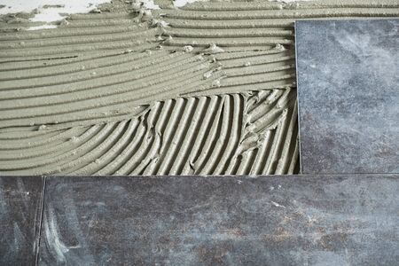 Dark grey ceramic floor tiles laid on applied adhesiveの写真素材
