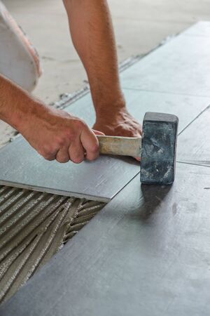 Worker placing ceramic floor tiles on adhesive surfaceの写真素材