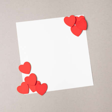 Blank paper gift card arranged with red hearts on a beige background. Minimal valentines flat layの写真素材