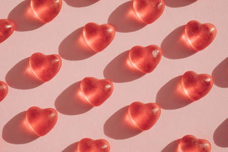 Red transparent gummy candy hearts pattern on light pink background. Valentines day minimal conceptの写真素材
