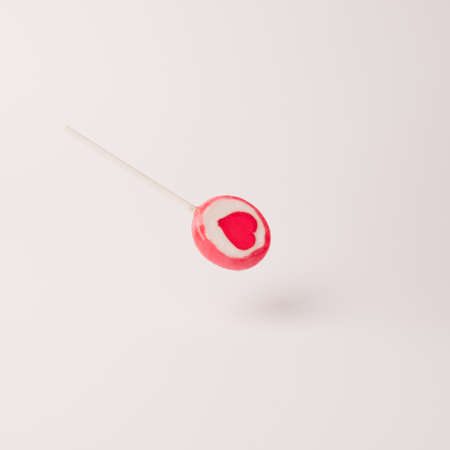 Flying pink lolipop with heart symbol on the pastel background. Sweet love minimal conceptの写真素材