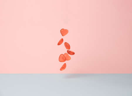 Flying gummy candy hearts above light blue and pink background. Love minimal conceptの写真素材