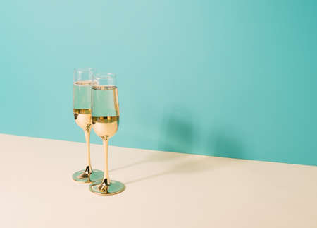 Two golden champagne glasses on a two tone pastel bacground. Celebration minimal conceptの写真素材