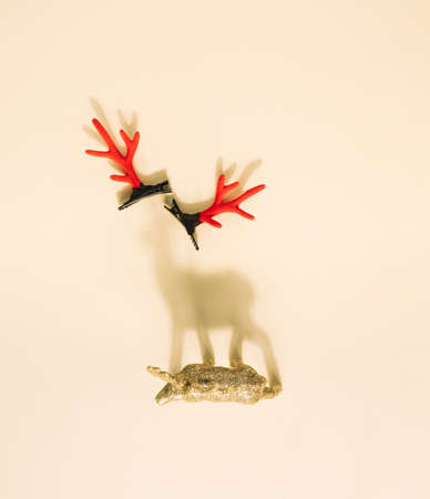 Reindeer Christmas ornament casting shadow on a yellow pastel background with red antlers. Minimal holidays conceptの写真素材