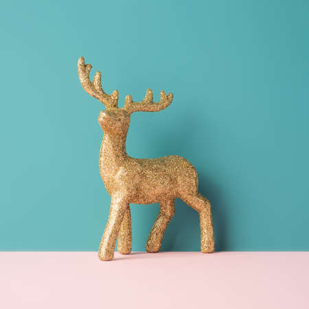 Golden glitter reindeer figurine against pastel blue background. Winter holidays minimal conceptの写真素材