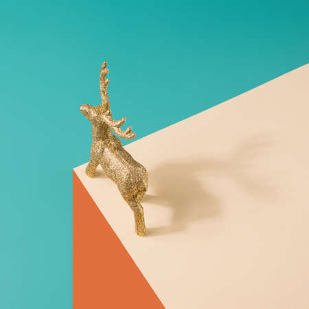 Golden reindeer figurine on a pastel surreal background. Christmas minimal concept.の写真素材