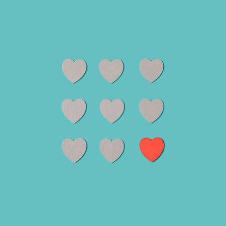 Gray wooden hearts arranged on a pastel turquoise background with one red heart. Authentic, romantic love minimal flat layの写真素材