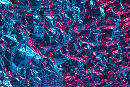 Crumpled aluminum foil with blue and pink light reflections. Futuristic abstract background.の写真素材