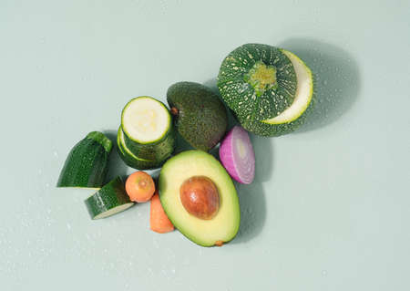 Fresh vegetables arranged on a light green background with water drops. Freshly prepared healthy foodの写真素材