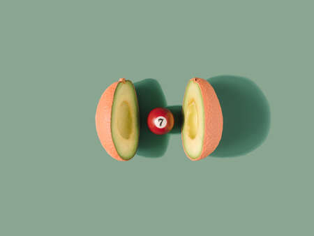 Open avocado revealing a pool ball instead of a seed. GMO food minimal concept.の写真素材
