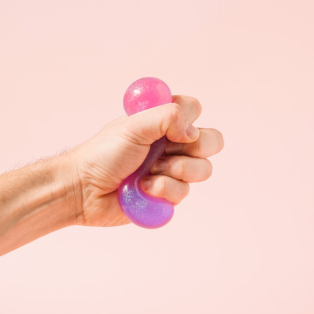 Hand squeezing violet purple glitter slime on a pastel pink background. Immersive reality conceptual background.の写真素材