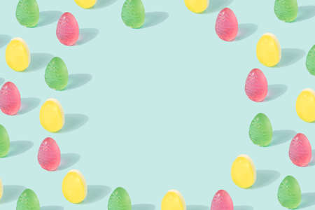 Easter eggs pattern with copy space made of colorful soft candy on a pastel blue background. Happy Easter minimal backdrop.の写真素材