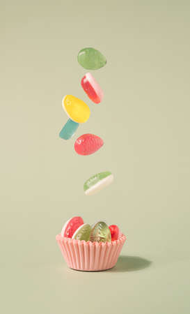 Easter eggs soft candy falling in the pastel pink paper cup. Happy Easter minimal backgroundの写真素材