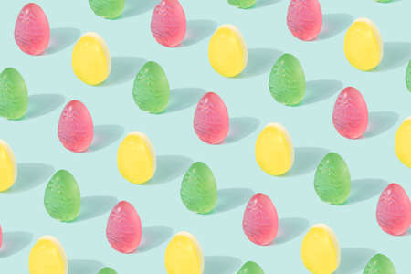 Easter eggs pattern made of colorful soft candy on a pastel blue background. Happy Easter minimal...
