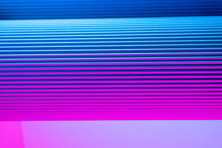 Neon hues over corrugated magenta and blue background. Futuristic abstract backdropの写真素材