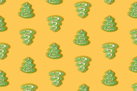 Gingerbread Christmas tree cookies arranged on a pastel yellow background. Merry Xmas colorful...