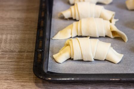 Raw croissants or crescent rolls with cheese filing before baking. Classic French pastry made.