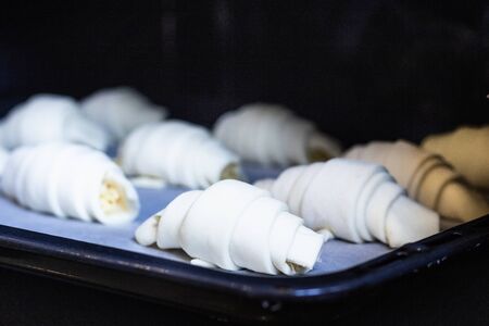 Raw croissants or crescent rolls with cheese filing before baking. Classic French pastry made.の写真素材